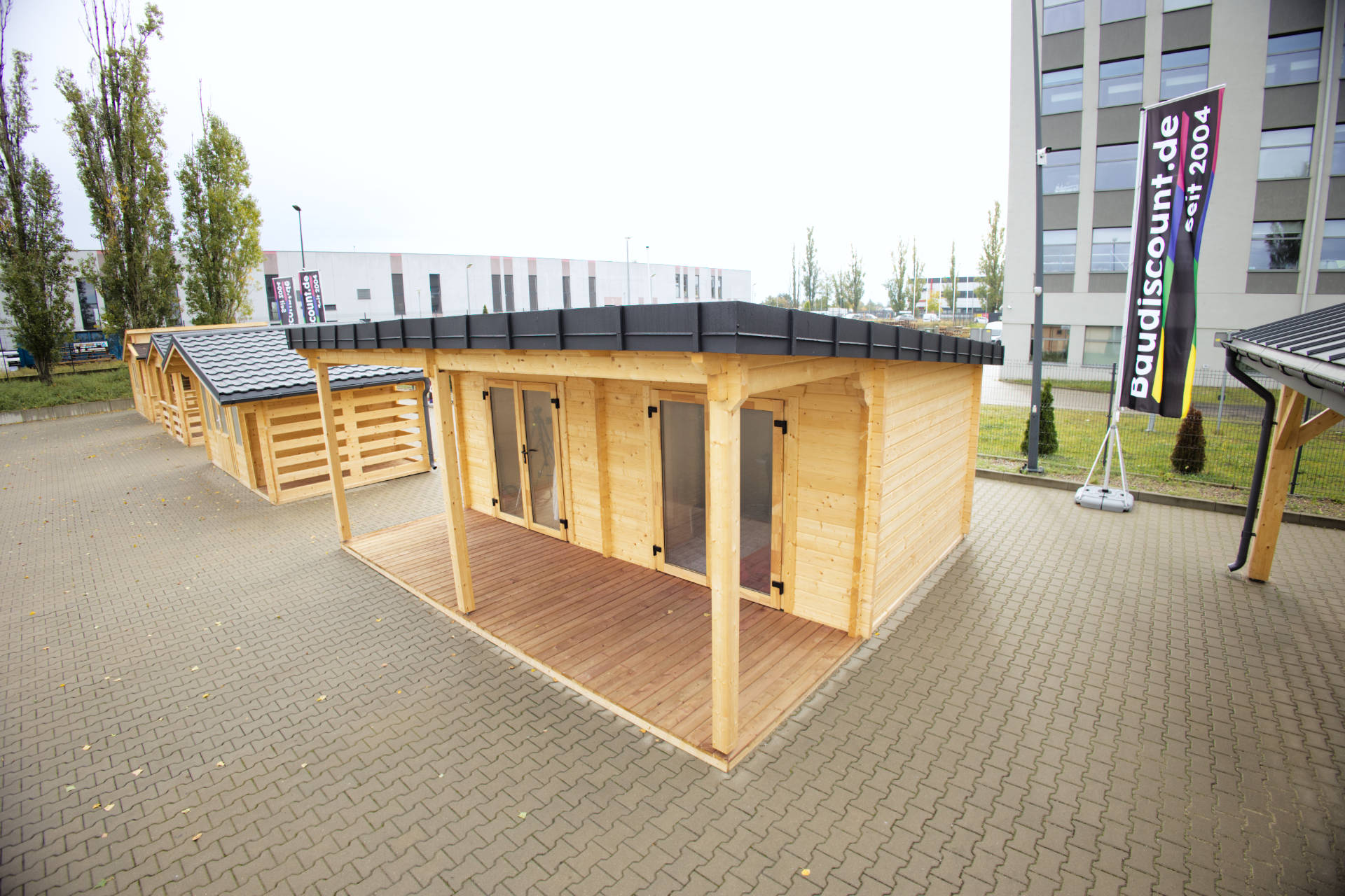 Reihe von Gerätehäusern aus Holz, ausgestellt auf gepflastertem Außenbereich